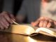 Man reading the Bible in dim light